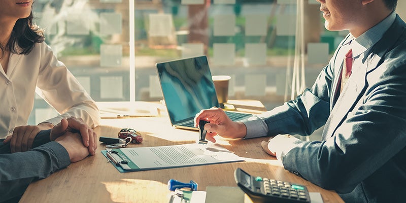 man sitting at desk with computer and paperwork
